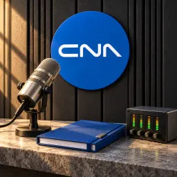 Broadcast microphone and signal meters in a studio with the round blue CNA mark on the wall