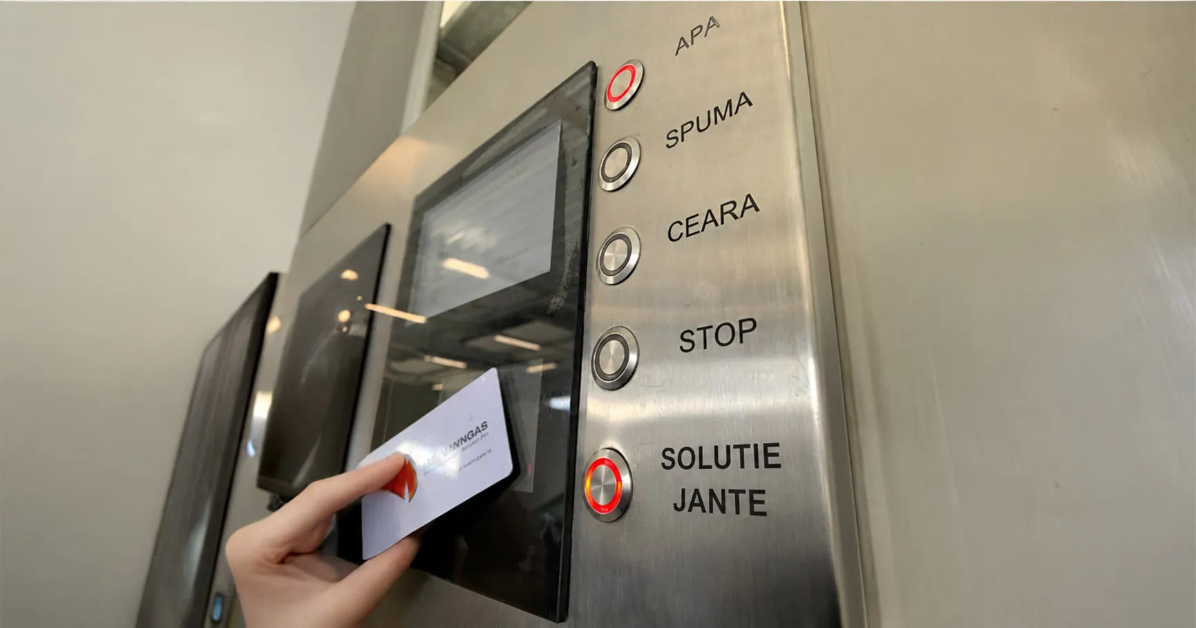 Hand holding a card to a stainless-steel self-service carwash panel with program buttons