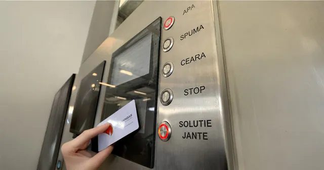 Hand holding a card to a stainless-steel self-service carwash panel with program buttons